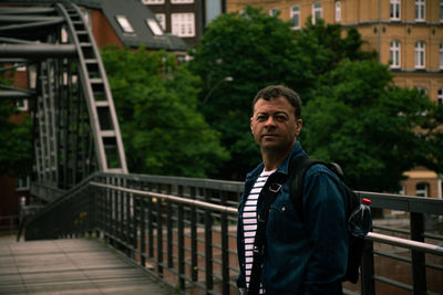 Portrait of mature man standing against railing outdoors