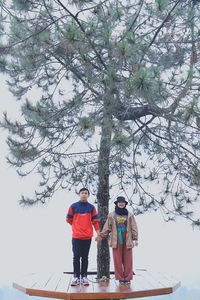 Full length of woman standing by tree