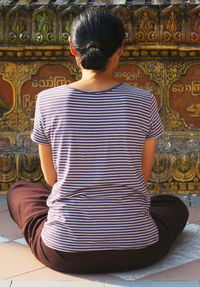 Rear view of woman sitting in temple