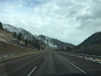 Road by mountains against sky