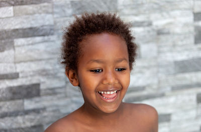 Close-up of smiling boy standing by wall outdoors