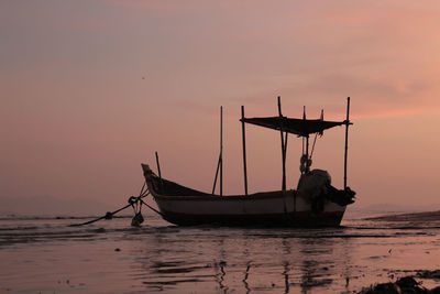 Fishing boat in sea against sky during sunset