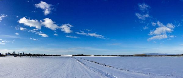 Panoramic view of snowcapped landscape against blue sky