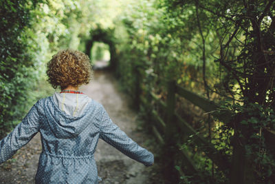 Rear view of woman standing in forest