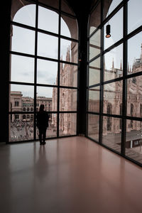 Woman looking at milan cathedral through glass window