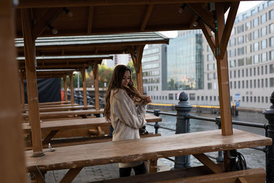 Young woman standing by table in city