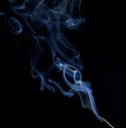 Incense stick smoke against black background