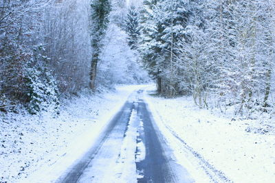 Road amidst snow covered landscape during winter