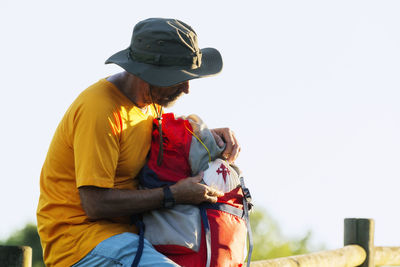 Man holding seashell on backpack against clear sky