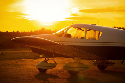 Airplane on runway against sky during sunset