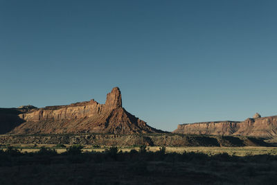 Rock formations on landscape against clear blue sky