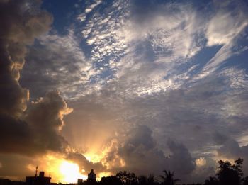 Low angle view of silhouette trees against dramatic sky