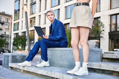 Businessman with laptop looking away to woman outdoors