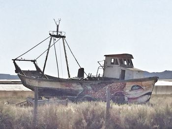 Abandoned boat on field against clear sky