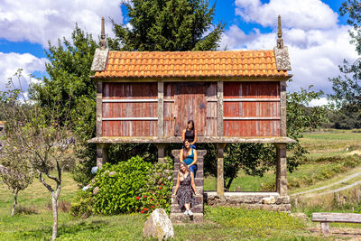 Women sitting by wooden built structure against sky