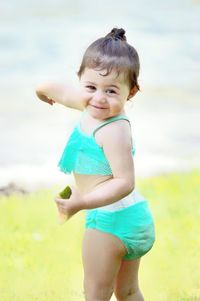 Portrait of cute girl holding fruit while standing outdoors