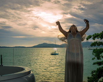 Woman standing by boat on sea against sky