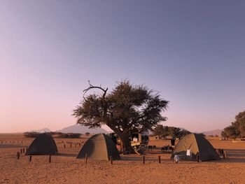 Tents at desert against sky during sunset