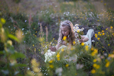 Full length of girl with yellow flowers on field
