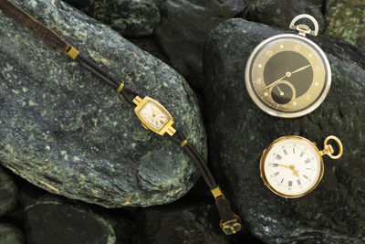 Close-up of pocket watch and wristwatch on rocks