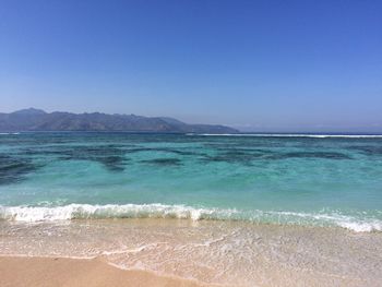 Scenic view of beach against clear blue sky
