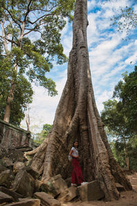 Full length of man standing on tree trunk against sky