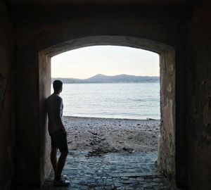 Rear view of man standing in tunnel at beach