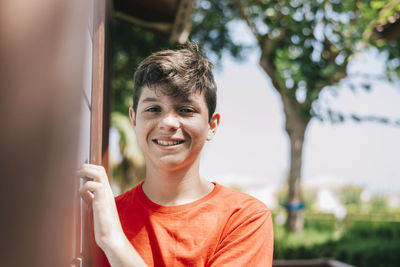 Portrait of smiling teenage boy outside house