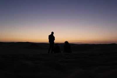 Silhouette man standing on land against sky during sunset