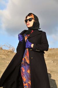 Portrait of woman wearing sunglasses while standing at desert
