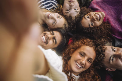 Portrait of cheerful teenage girl taking selfie with friends at park