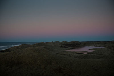 Scenic view of beach against sky at sunset