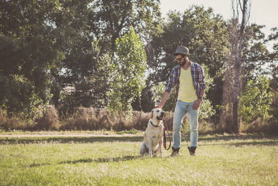 Mid adult man with dog standing on grassy field