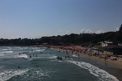 People on beach by city against sky