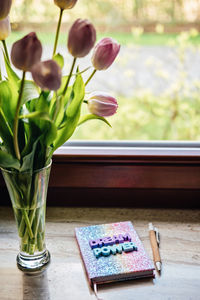 Big dream word on pop color rainbow unicorn shiny notepad and tulips on wooden table. motivation