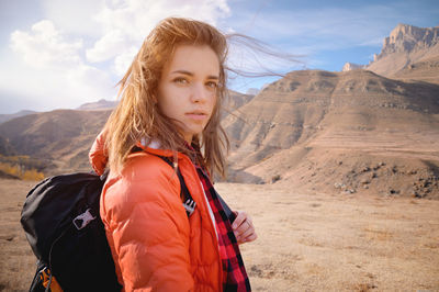 Young attractive jewish woman in a down jacket and with a backpack against the backdrop