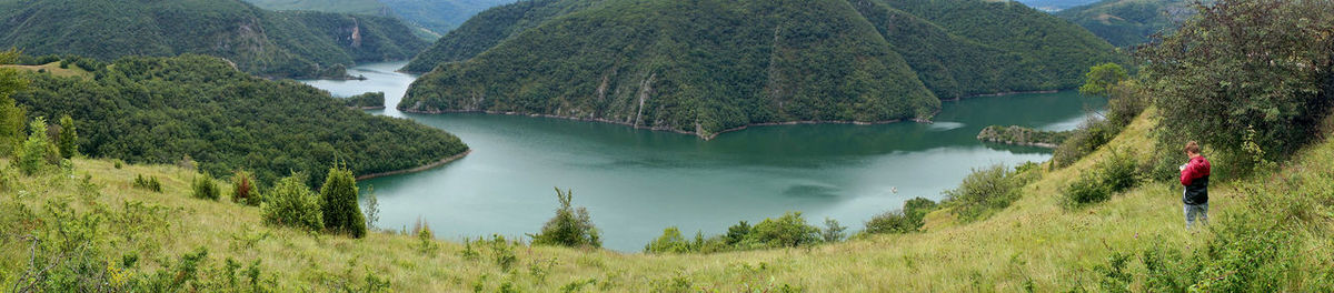 Man standing at lakeshore against mountains