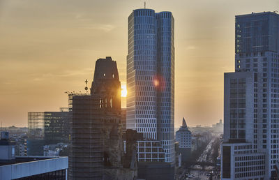 Modern buildings in city against sky during sunset