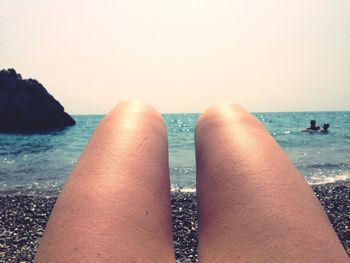 Low section of woman on beach against clear sky