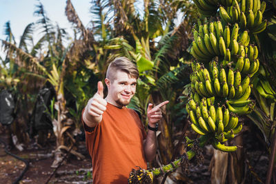 Portrait of young woman standing amidst plants