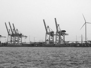 Cranes at commercial dock against clear sky