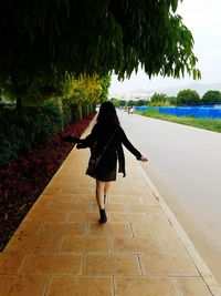 Rear view of woman walking on footpath