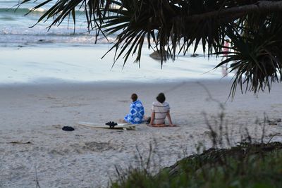Men sitting on beach against sky