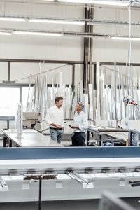 Male engineers discussing while standing in manufacturing industry