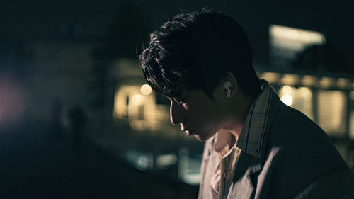 Close-up portrait of young man looking away at night