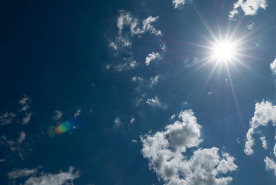 Low angle view of sunlight streaming through clouds