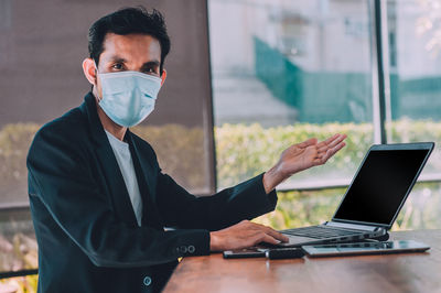 Portrait of businessman wearing mask sitting at office