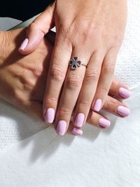 Cropped image of woman with painted fingernails wearing ring on table