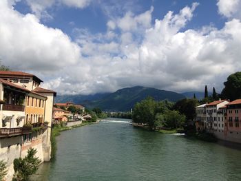 Buildings by river against sky in city