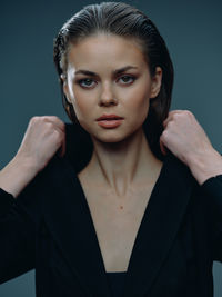 Portrait of young woman against black background